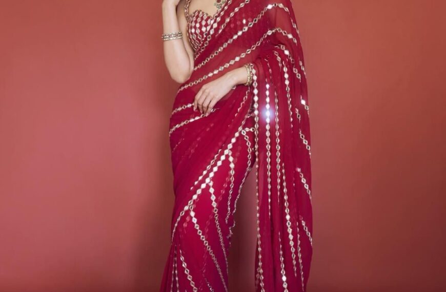 Sreeleela’s ruby red georgette sari is cut through with lines of mirror work